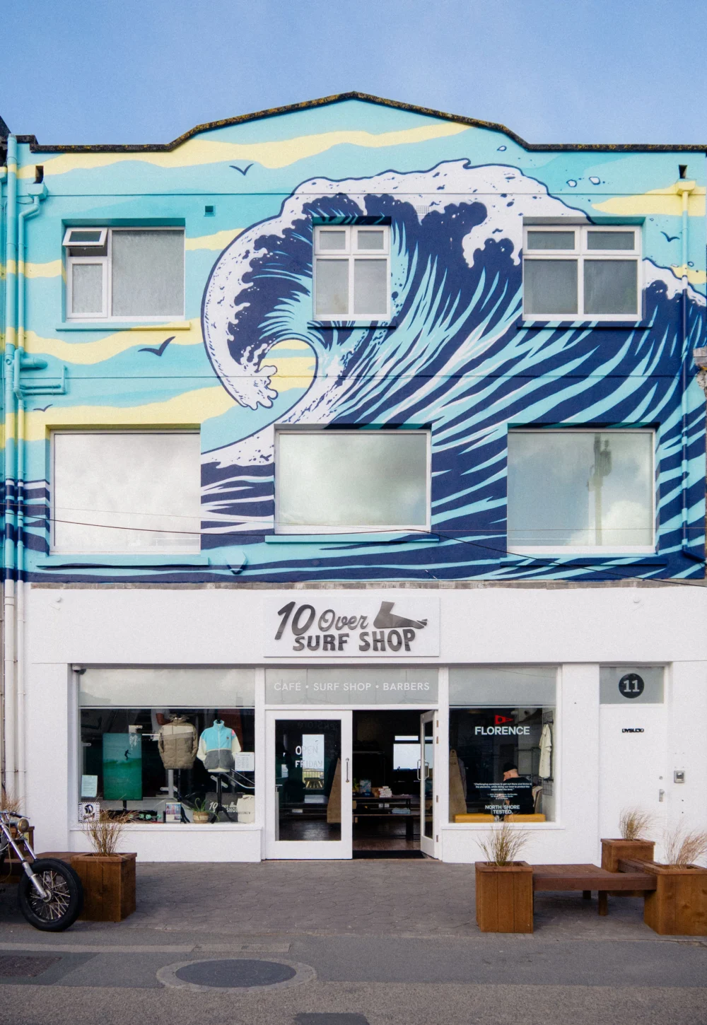 The 10 Over Surf Shop storefront beneath a blue wave mural on Cliff Road in Newquay.