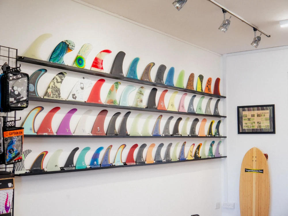 Rows of colourful surfboard fins on display inside 10 Over Surf Shop in Newquay.